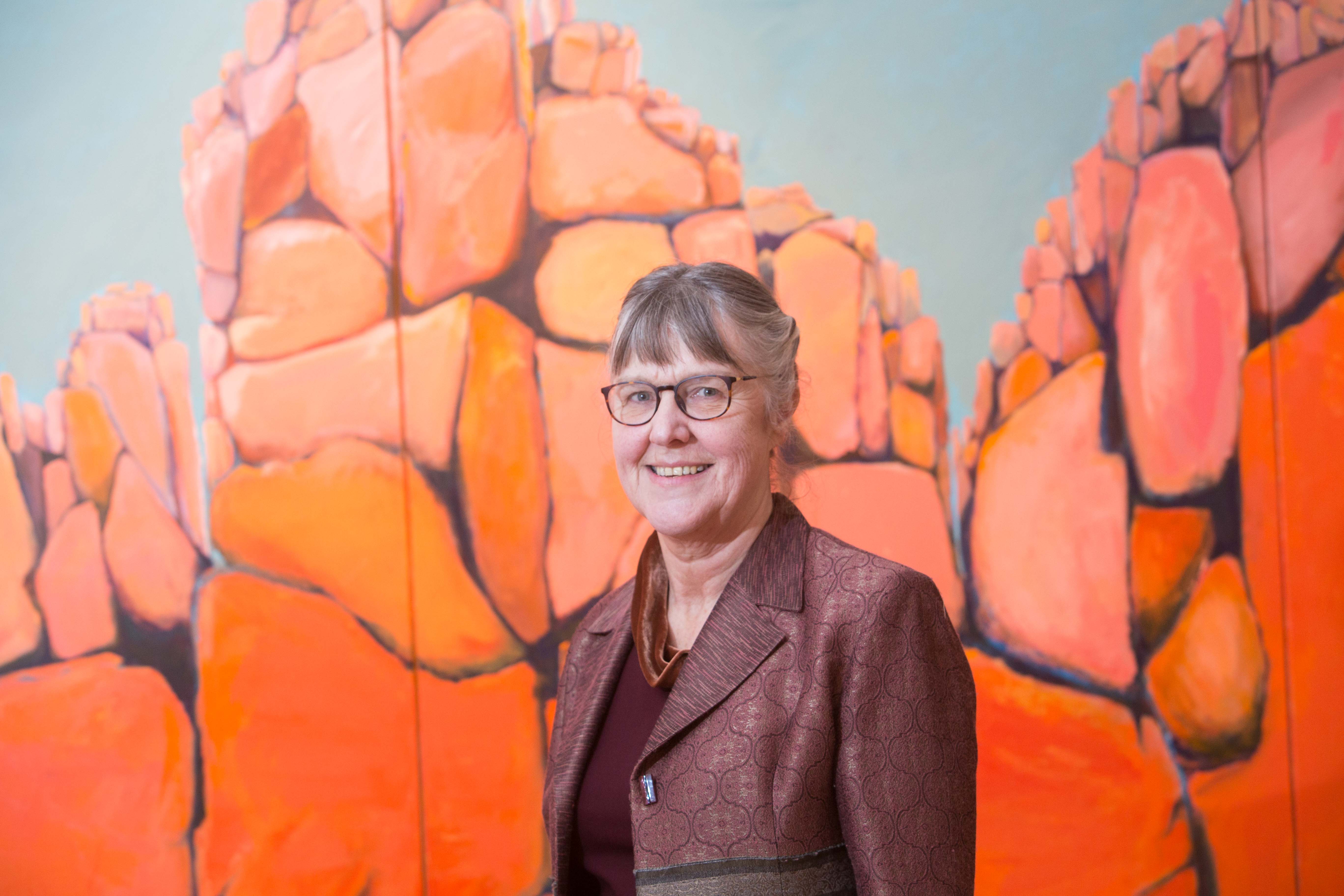 Artist Anna Moore in front of her painting "Safe Place For Rhino - Waterburg Plateau"